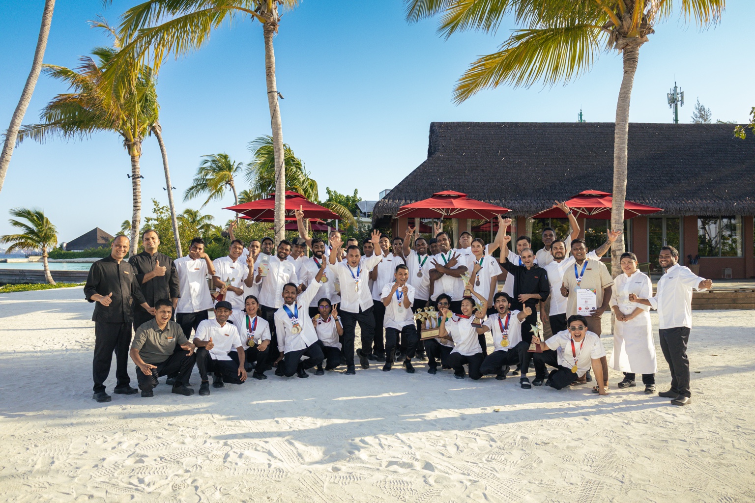 The dusitD2 Feydhoo Maldives culinary team celebrating on the beach with medals and trophies